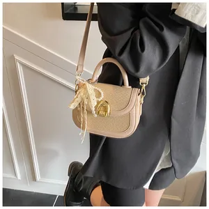 Détail du sac selle avec texture tissée, garniture en cuir et charme perle avec nœud