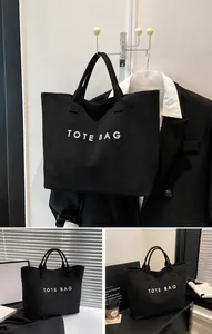 Λεπτομέρεια μαύρης σουέτ τσάντας tote με λευκό κείμενο και ενισχυμένες λαβές