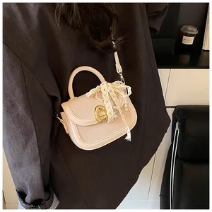 Détail du sac selle crème avec texture tressée, boucle dorée et décorations en perles