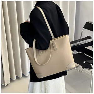 Detailed side view of a beige faux leather tote bag worn as an underarm shoulder bag