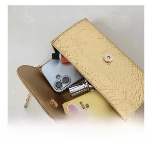 Internal capacity of gold textured envelope crossbody bag showing space for phone and lipstick
