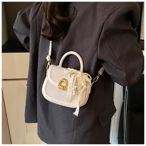 Détail du sac selle avec nœud en dentelle et pendentif perle sur un blazer gris