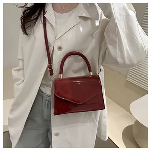 Détail du sac en cuir verni bordeaux avec rabat en V et bandoulière réglable
