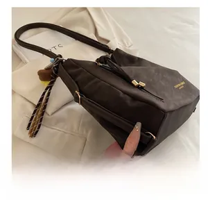 Detail of dark brown faux leather tote with golden hardware, plaid ribbon and bear charm