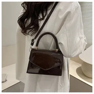 Détail du sac bandoulière élégant en cuir verni marron foncé avec texture brillante et bride