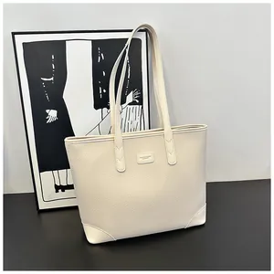 Detail of cream lychee leather tote bag showing fashion tag and textured surface