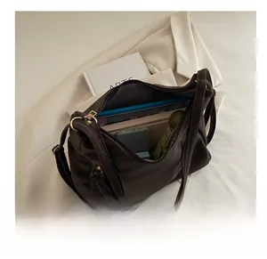 Spacious interior of a dark brown shoulder bag holding a tablet, books, and umbrella