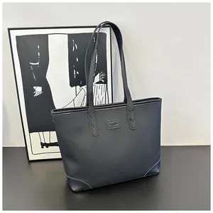 Detail of black pebbled leather tote bag with logo patch and reinforced bottom corners