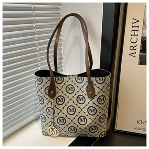 Detalle del bolso tote con diseño de rombos, asas de cuero y colgante dorado M