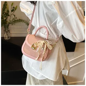 Détail du sac selle rose à texture tissée avec breloque perle et boucle dorée chic