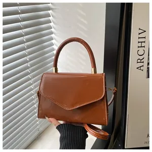 Détail d'un sac à main en cuir verni marron caramel avec finition brillante et boucles dorées