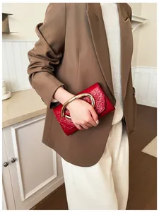 Detail of red wrinkled patent leather clutch bag with large oval gold metal handle