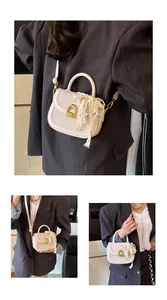 Détail du sac selle tissé blanc cassé avec boucle dorée et breloque en perles de dentelle