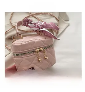Detailed macro view of pink quilted mini bag with gold zippers and a silk scarf handle