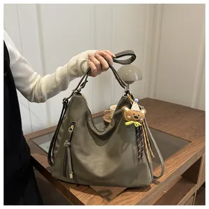 Detail view of large olive tote bag with side zipper tassel and cute bear charm