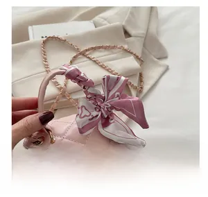 Detail of pink quilted mini bag with scarf-wrapped handle and gold chain strap