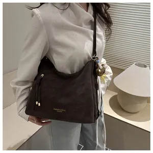 Detail of dark brown matte tote bag with teddy bear pendant and fashion gold lettering