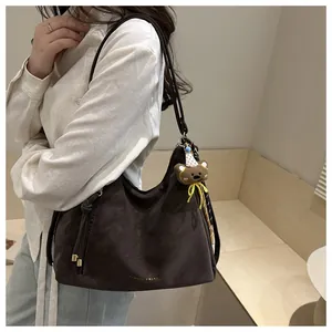 Detail of dark brown leather hobo bag with gold logo and cute bear charm pendant