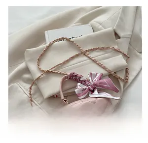 Pink quilted mini bag featuring silk scarf wrapped handle and gold ball pendant detail
