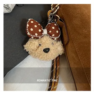 Nahaufnahme eines flauschigen Hundeanhängers mit gepunkteter Schleife an einer Ledertasche