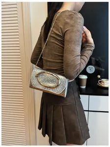 Detail of silver textured square bag featuring a gold oval clasp and slim chain strap