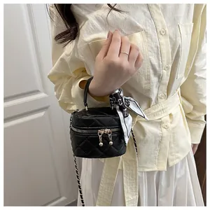 Detail of a black quilted vanity bag with a printed silk scarf on the golden chain strap
