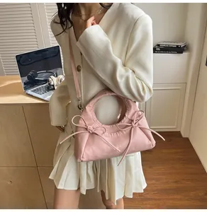 Close-up of a pink crescent tote bag with soft pleated texture and slim shoulder strap