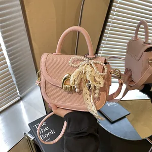 Sac à main rose avec nœud en perles et dentelle présenté dans un décor de miroir
