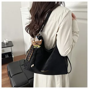 Close-up of black suede tote bag with cartoon bear charm and fringe detail