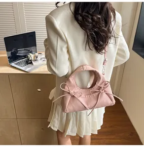 Detail view of a pale pink tote bag with double bows worn over a white blazer