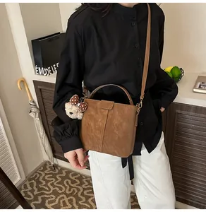 Brown suede bucket bag detail with adjustable strap and cute plush bear charm