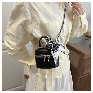 Close-up of black quilted mini bucket bag with silk scarf and gold chain strap