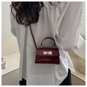 Detail view of a dark red patent leather handbag with a gold-tone metallic twist lock