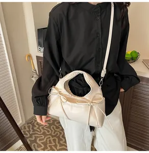 Detail of cream-colored faux leather tote bag featuring a decorative side bow and drawstrings