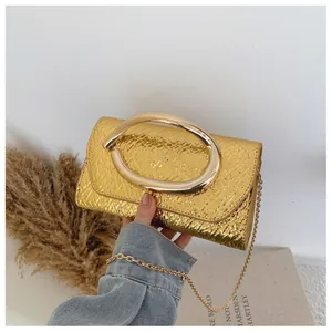 Detail of gold square clutch with embossed crocodile texture and metal C-handle