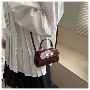 Detail of burgundy patent leather mini crossbody bag with golden twist lock closure