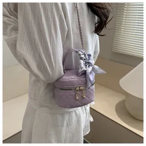 Detail of purple quilted mini box bag with gold metal ball zippers and silk scarf handle