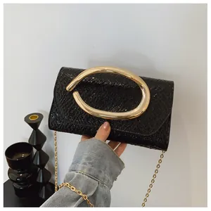 Detail of glossy black embossed patent leather with a large gold oval metal handle