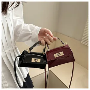 Detail of glossy black and wine red mini handbags with elegant gold metal twist locks