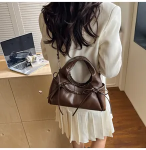 Detail of dark brown faux leather tote with ruched handle and bow accents on a model
