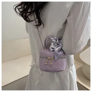 Detail of lavender quilted mini vanity bag with silk scarf on handle and chain strap