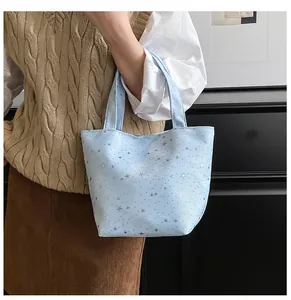 Detail of light blue canvas tote bag with silver star prints and sturdy handles