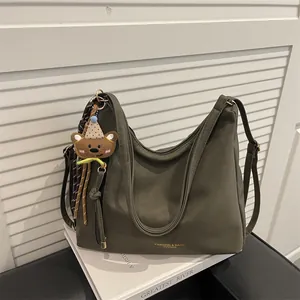 Olive green large capacity tote bag with plush bear charm and woven tassel detail