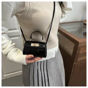 Close-up of a glossy black patent leather mini handbag with a gold twist-lock fastener