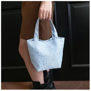 Close-up of light blue canvas tote bag featuring stylish silver star patterns and handles