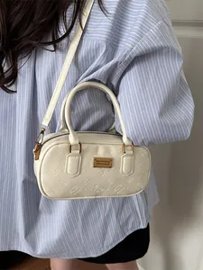Bolso Boston blanco crema con relieve de gato llevado por modelo con atuendo elegante