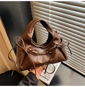 Close-up of brown PU leather cloud bag with soft pleats and elegant bow detailing