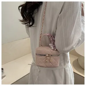 Detail of light pink quilted mini crossbody bag with gold chain and silk scarf handle