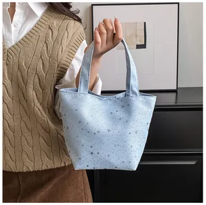 Close-up of light blue canvas tote bag with silver star patterns and bow detail