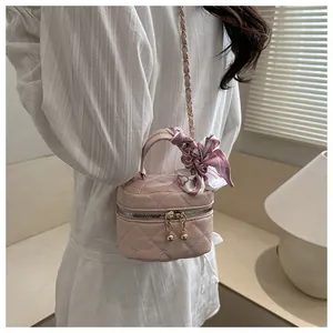 Detailed view of pink quilted mini crossbody bag with silk scarf and chain strap on model